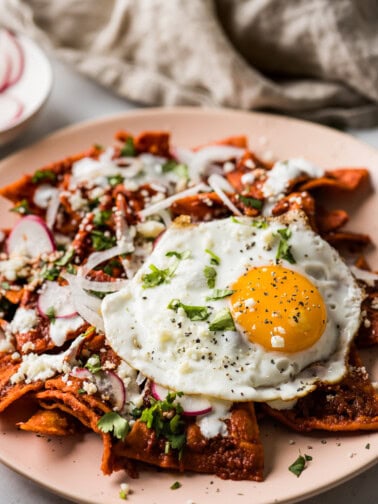 A plate of chilaquiles topped with a fried eggs.