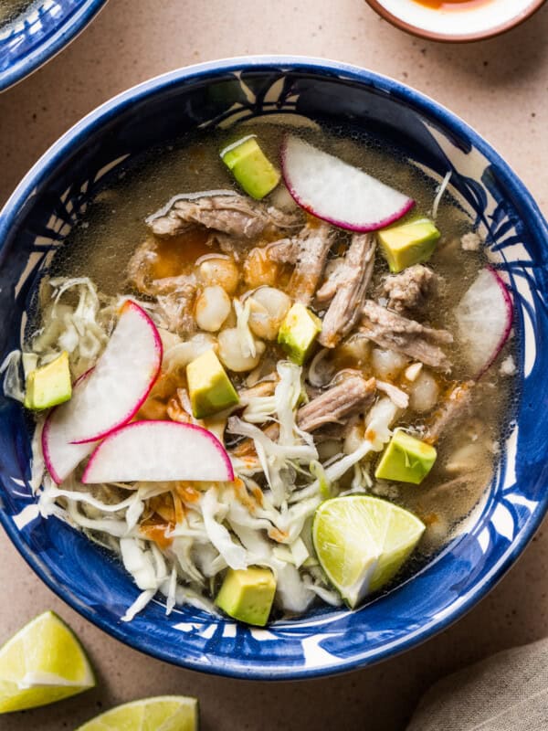 Pozole blanco in a bowl topped with avocado, radishes, and thinly sliced cabbage.