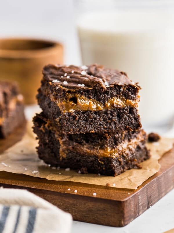 Dulce de Leche Brownies stacked on top of one another to showcase the layer of dulce de leche in the middle.