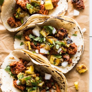 Tacos al pastor topped with grilled pineapple, cilantro, and white onion.