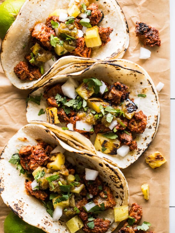 Tacos al pastor topped with grilled pineapple, cilantro, and white onion.