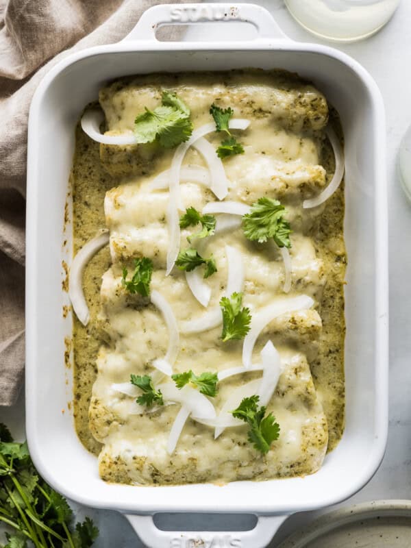 Enchiladas Suizas in a baking dish garnished with onions and cilantro.