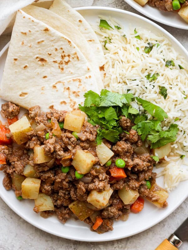 Mexican picadillo on a plate with rice and flour tortillas.