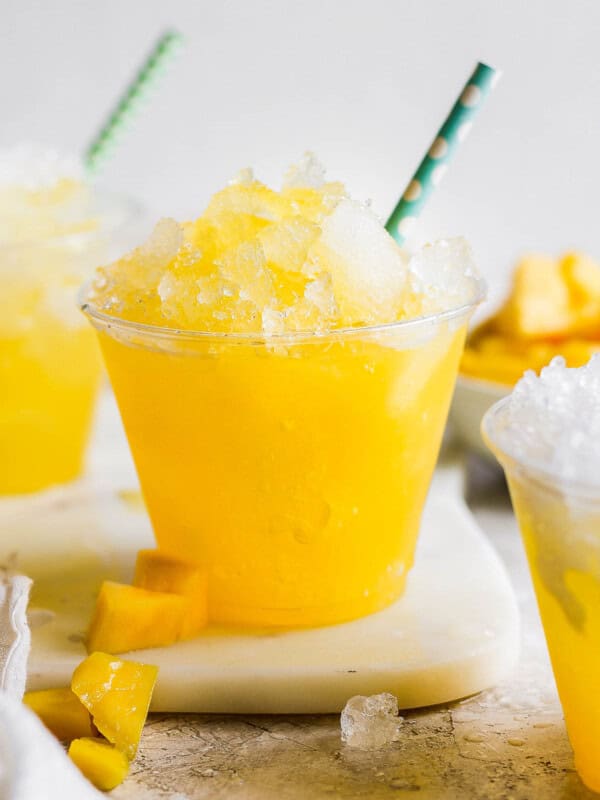 Raspados Mexicanos shaved ice in a cup with a straw made with a sweet mango syrup