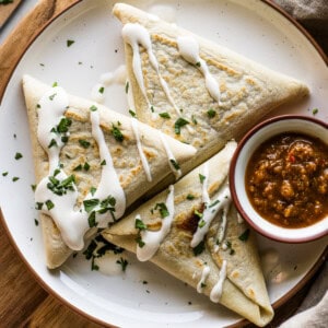 Tetelas on a plate served with Mexican crema, salsa, and chopped cilantro.