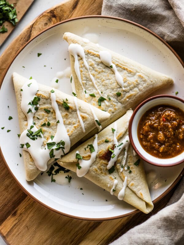 Tetelas on a plate served with Mexican crema, salsa, and chopped cilantro.