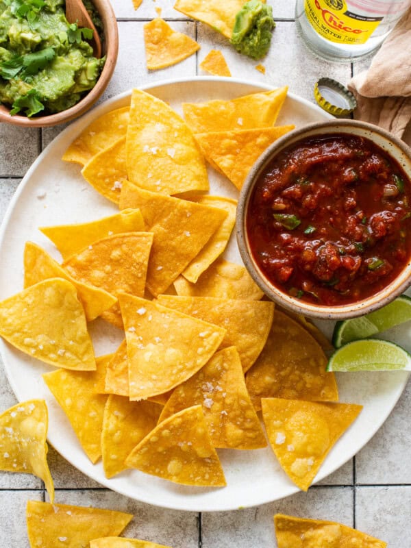 Homemade tortilla chips on a plate seasoned with flaky sea salt.