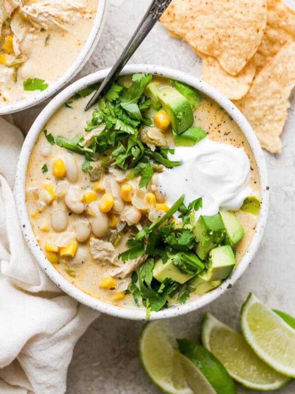 White chicken chili in a bowl garnished with cilantro, avocado, and sour cream.