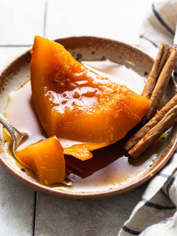 A slice of tender calabaza en tacha on a plate served with a piloncillo syrup.