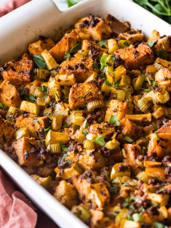 A baking dish of chorizo stuffing garnished with fresh parsley and made with apples, onion, and celery.