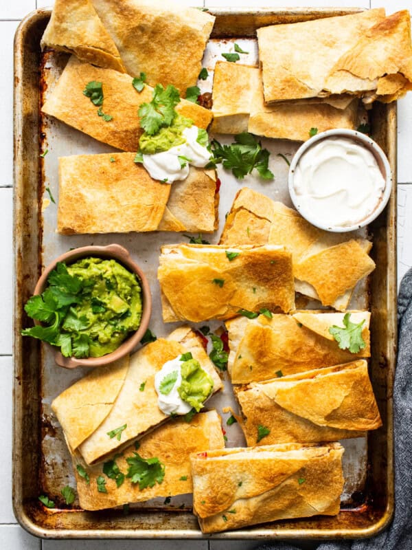 Sheet pan quesadillas on a sheet pan served with sour cream and guacamole.