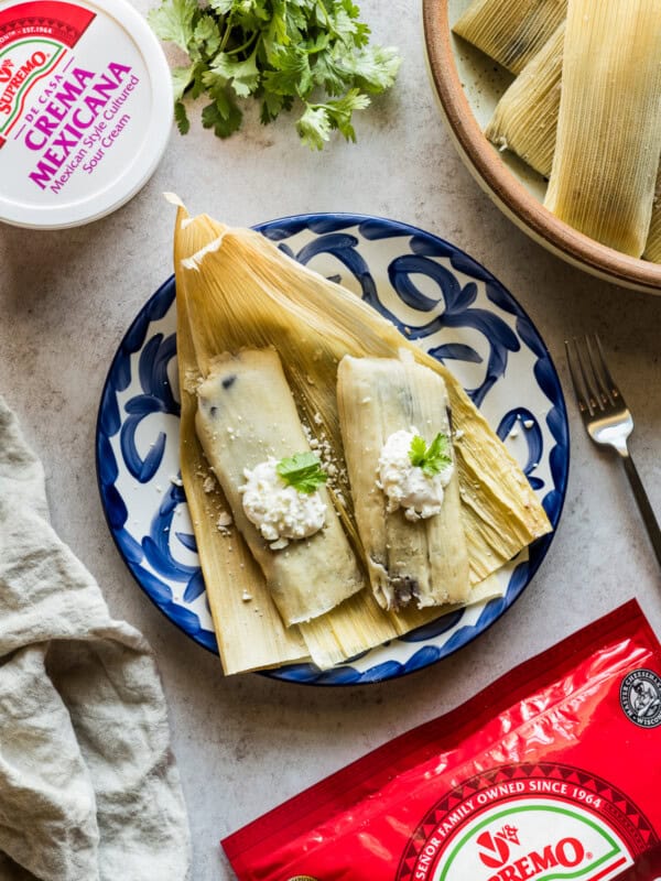 Black bean and cheese tamales garnished with crema and cotija cheese.