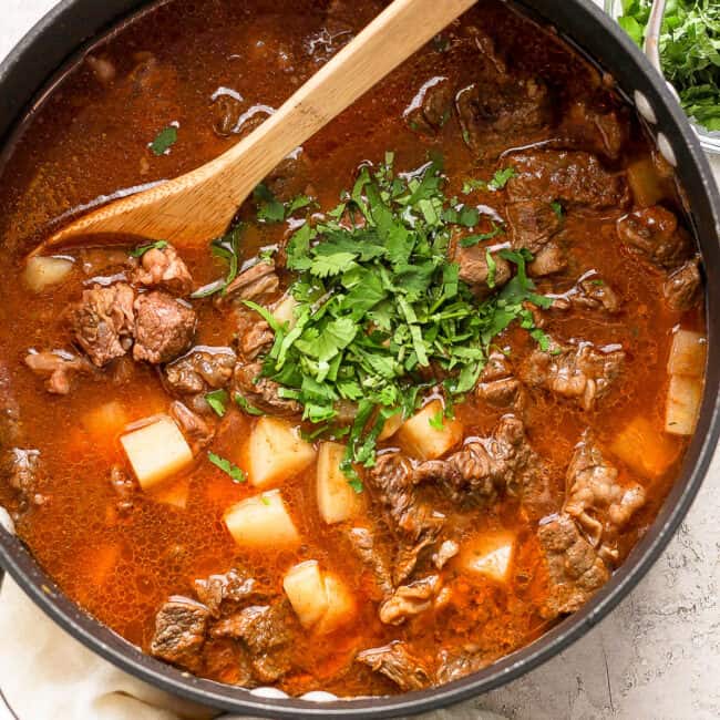 Carne con papas in a pot with cilantro stirred in.