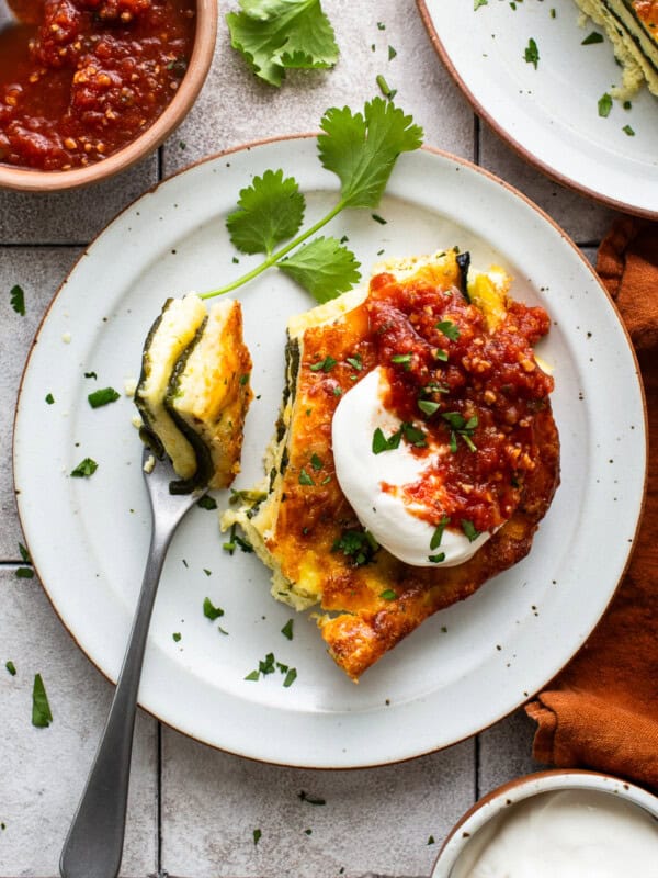 A slice of chile relleno casserole served with sour cream and salsa.