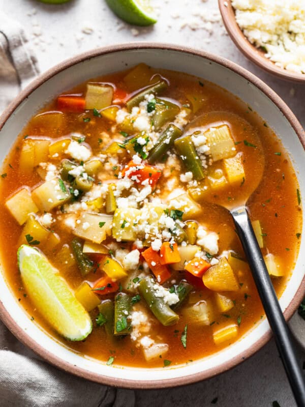 Mexican Vegetable Soup in a bowl garnished with lime juice and cotija cheese.