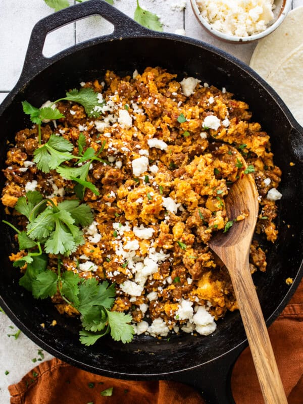 Chorizo and eggs in a skillet garnished with queso fresco and cilantro.