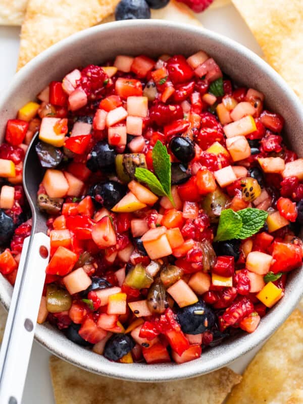 Fruit salsa in a bowl with a spoon and a mint leaf in the middle.