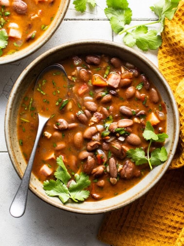 A bowl of charro beans topped with fresh cilantro on a table.