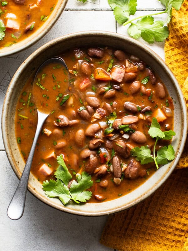 A bowl of charro beans topped with fresh cilantro on a table.