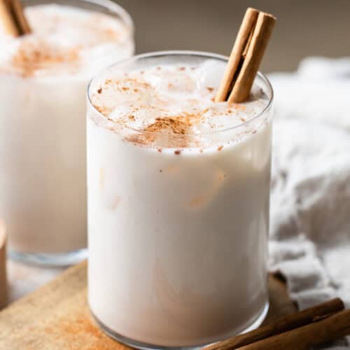 A glass of horchata on a table garnished with ground cinnamon and poured over ice.