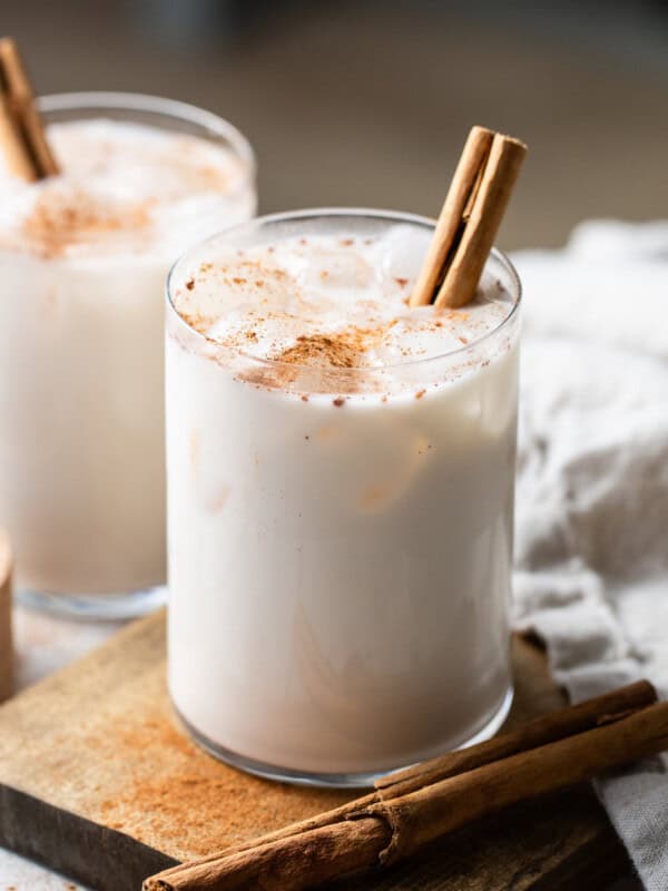 A glass of horchata on a table garnished with ground cinnamon and poured over ice.