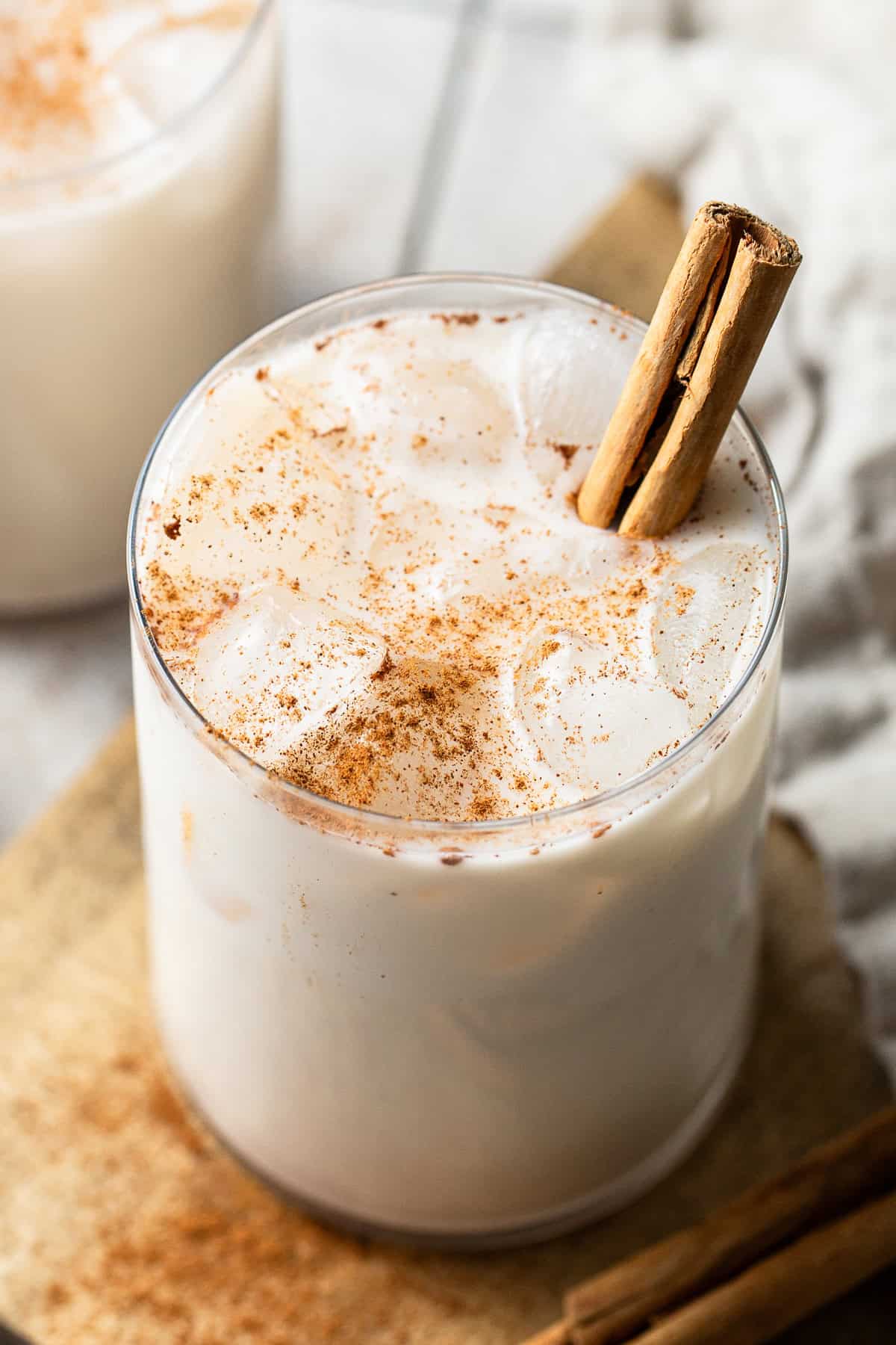 Horchata served over ice in a glass and garnished with a dusting of ground cinnamon and a cinnamon stick