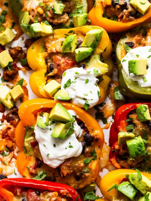 Mexican stuffed peppers served with a dollop of sour cream, avocado, and cilantro.