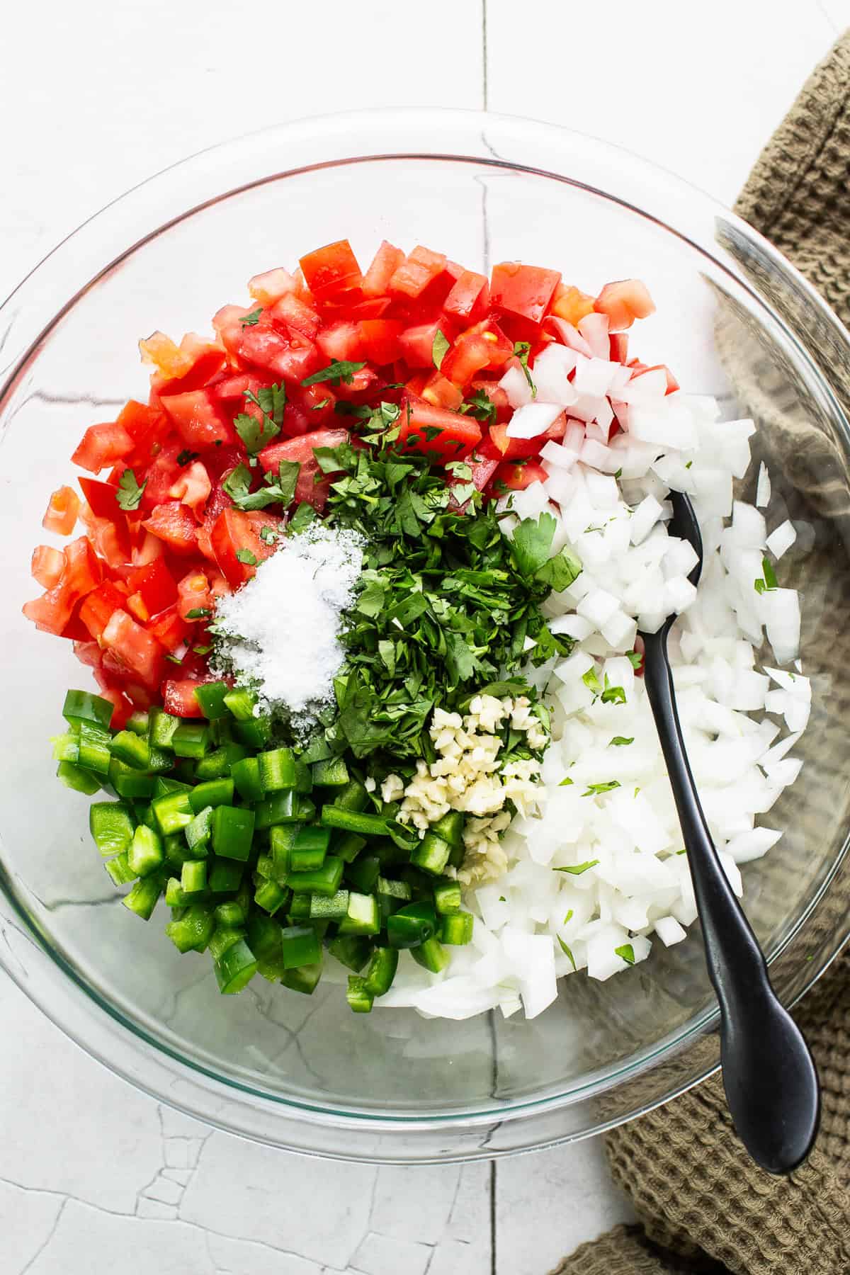 Tomatoes, onions, jalapeños, garlic, and salt added to a bowl to make a pico de gallo recipe