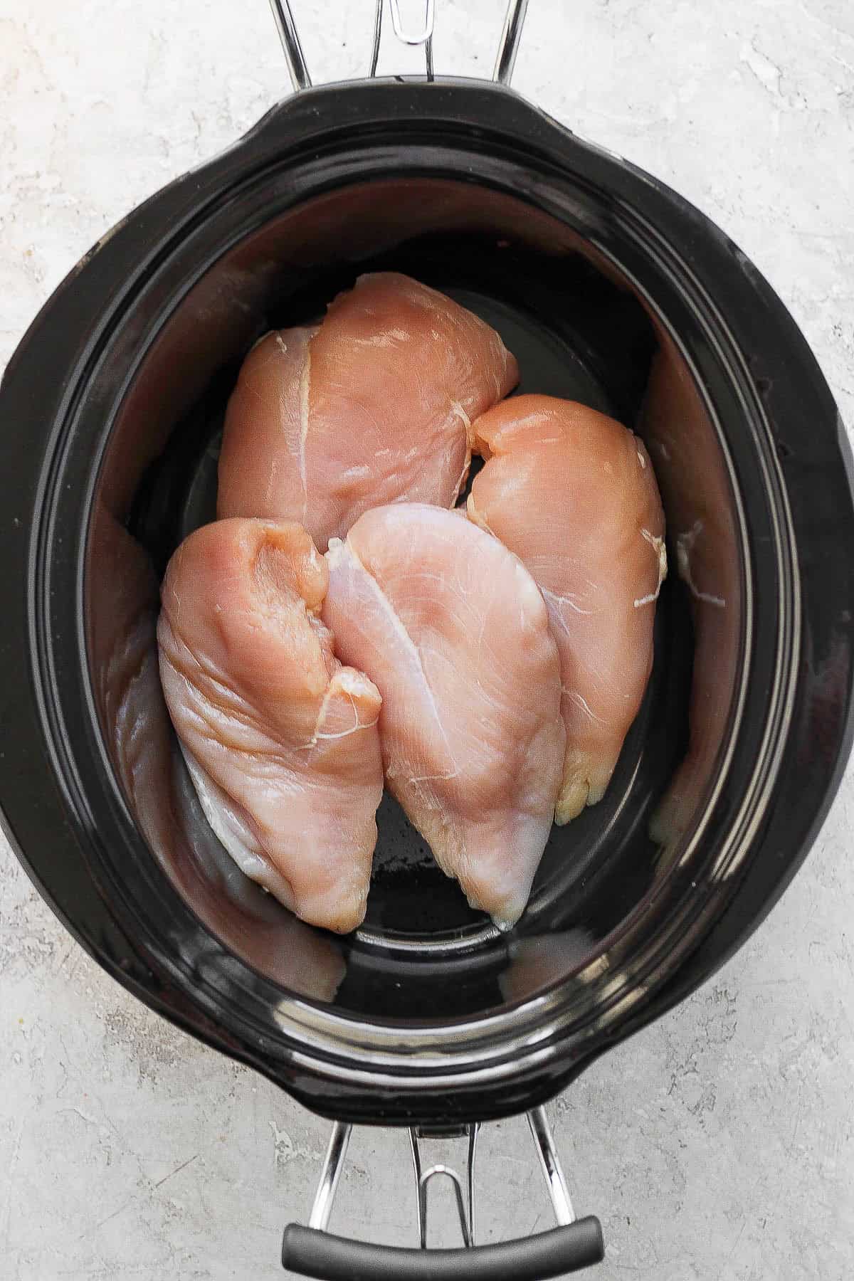 Raw chicken added to a crockpot