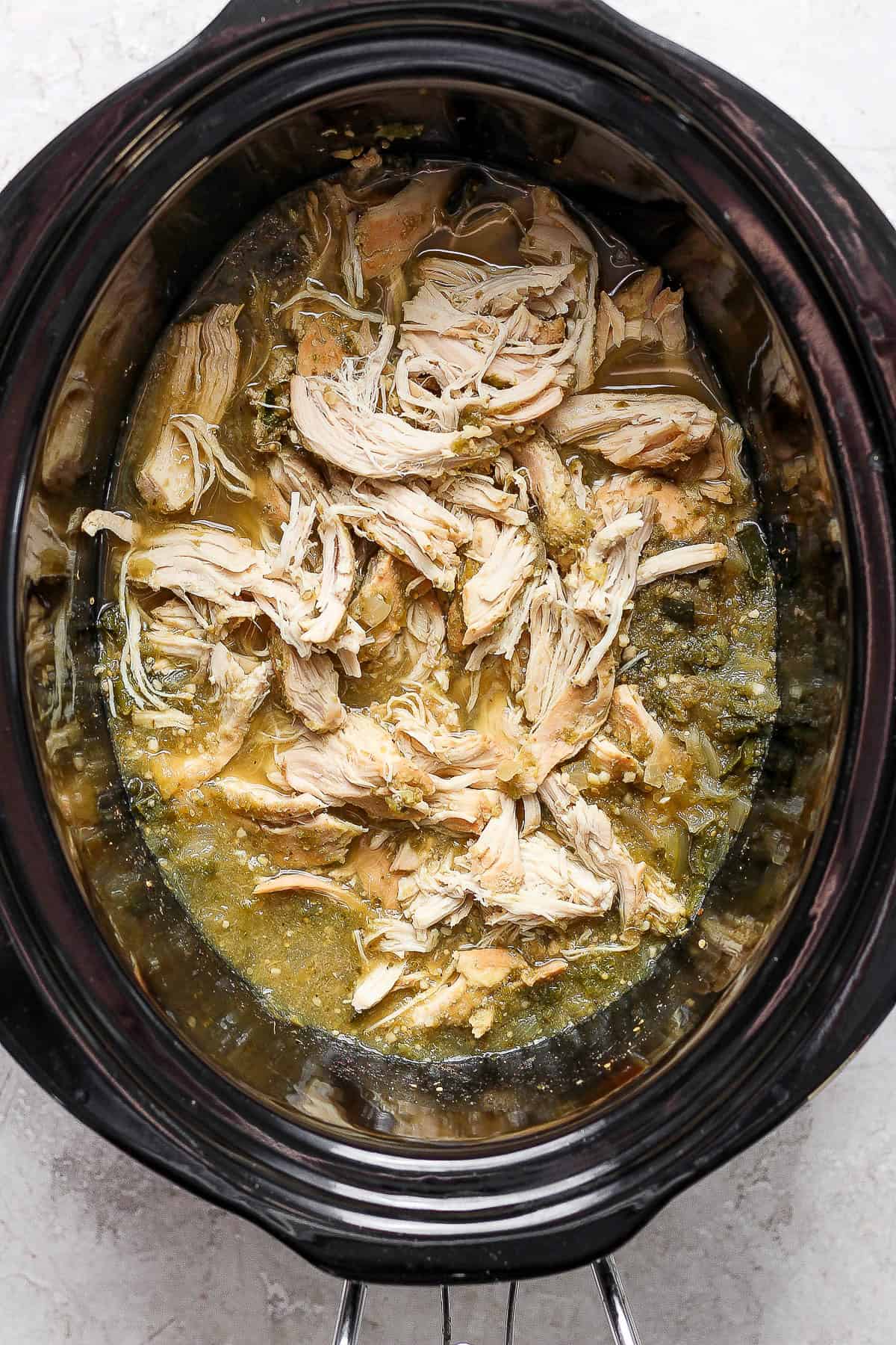 Cooked chicken has been shredded inside the crockpot