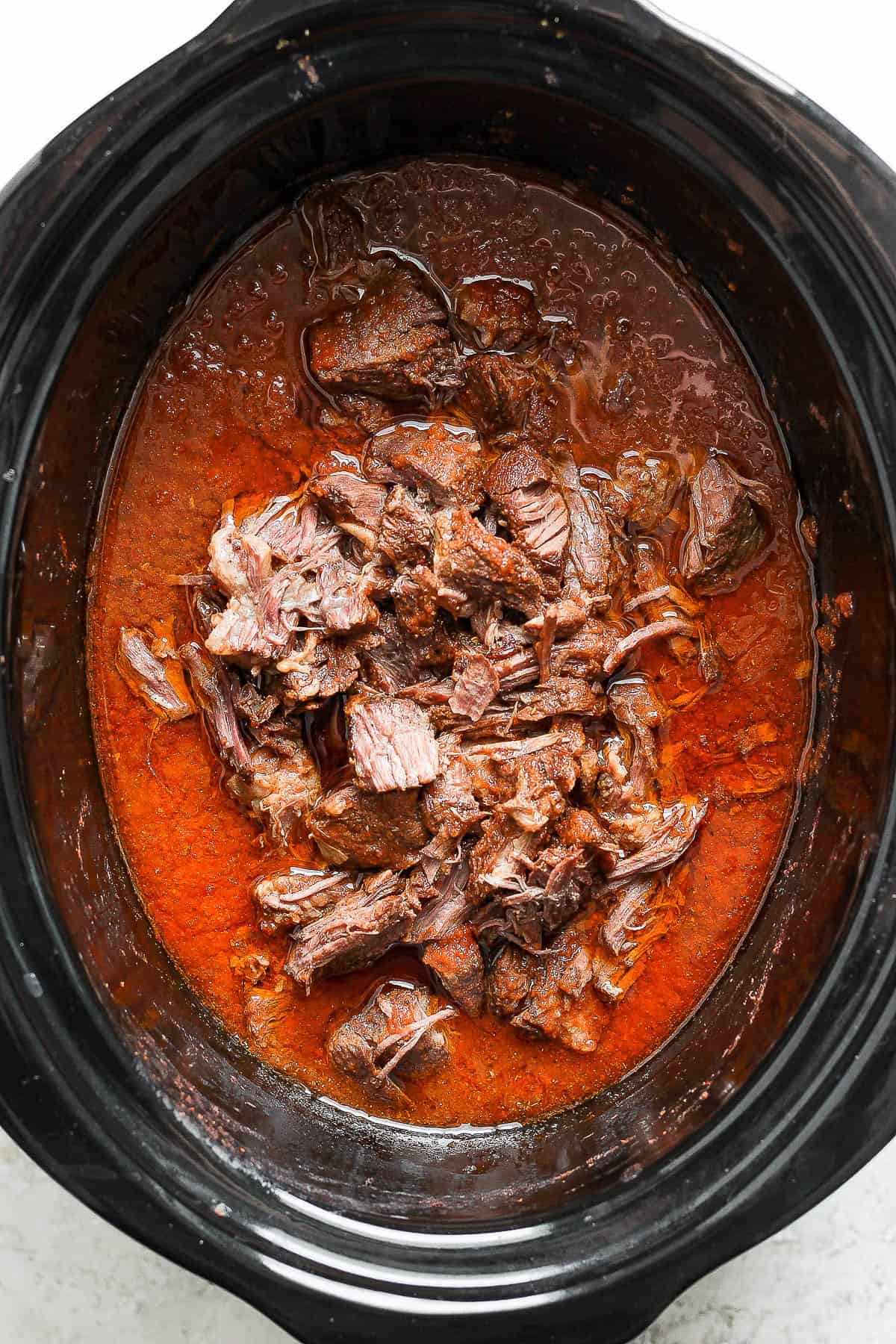 Beef is shredded and added back into the crockpot 