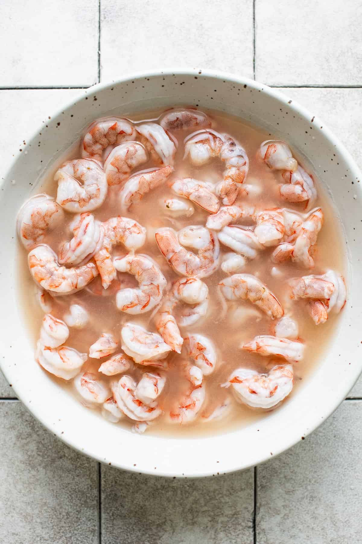 Shrimp in lime juice in a bowl.