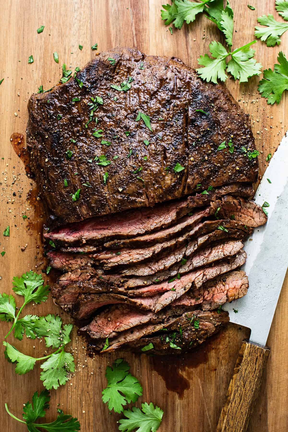 Cooked steak cut into slices on a cutting board ready to rest 