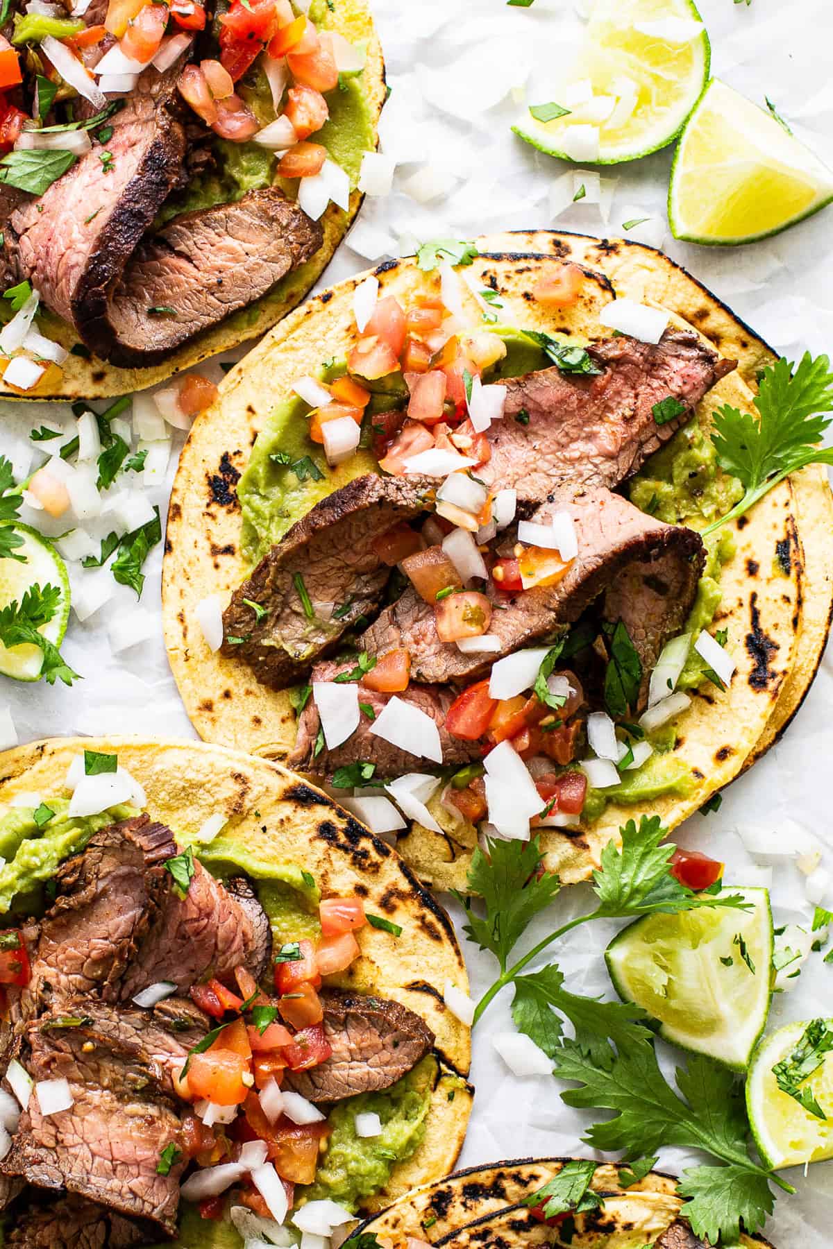 Flank steak tacos plated with pico de gallo and limes.