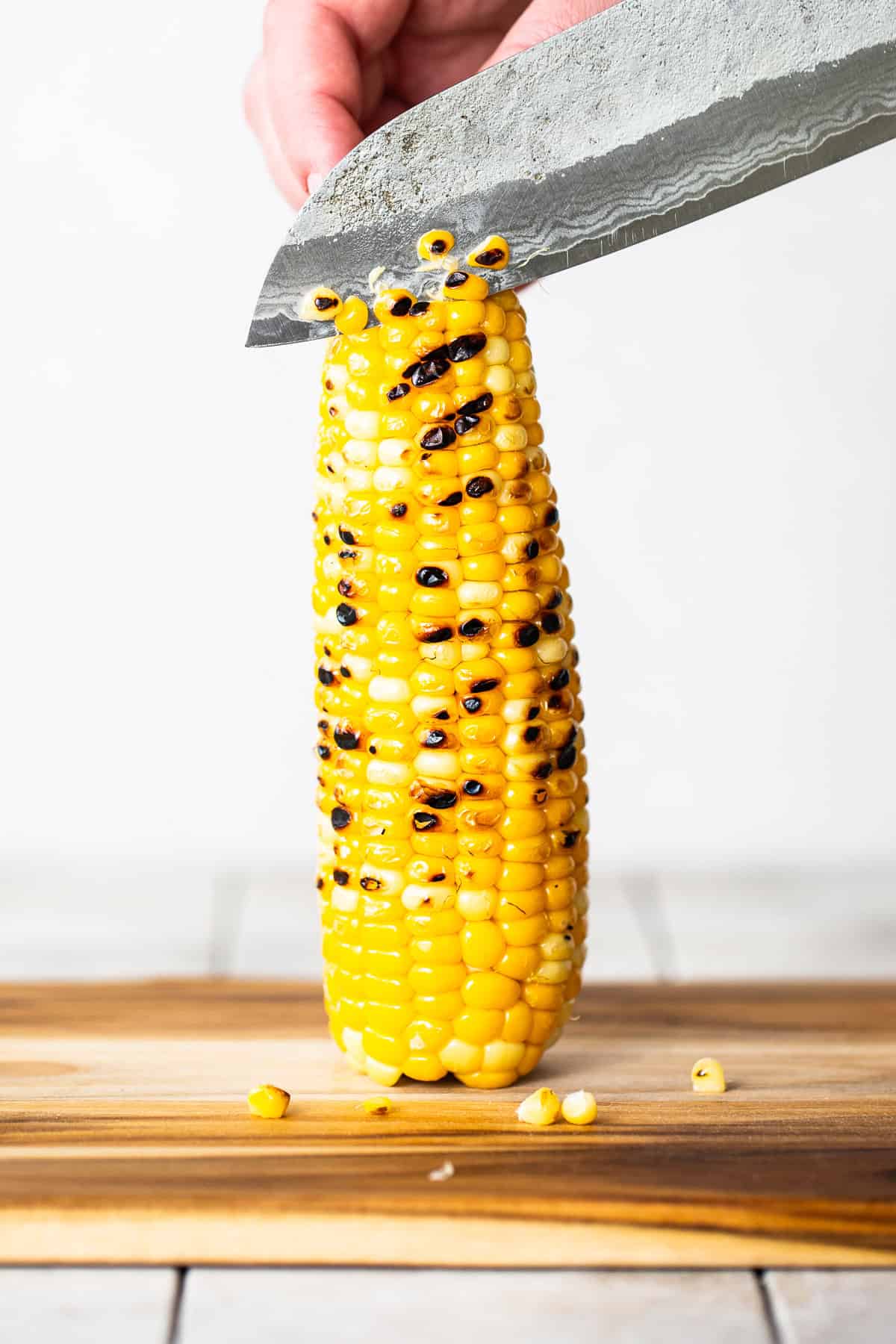 Grilled corn being sliced off the cob.
