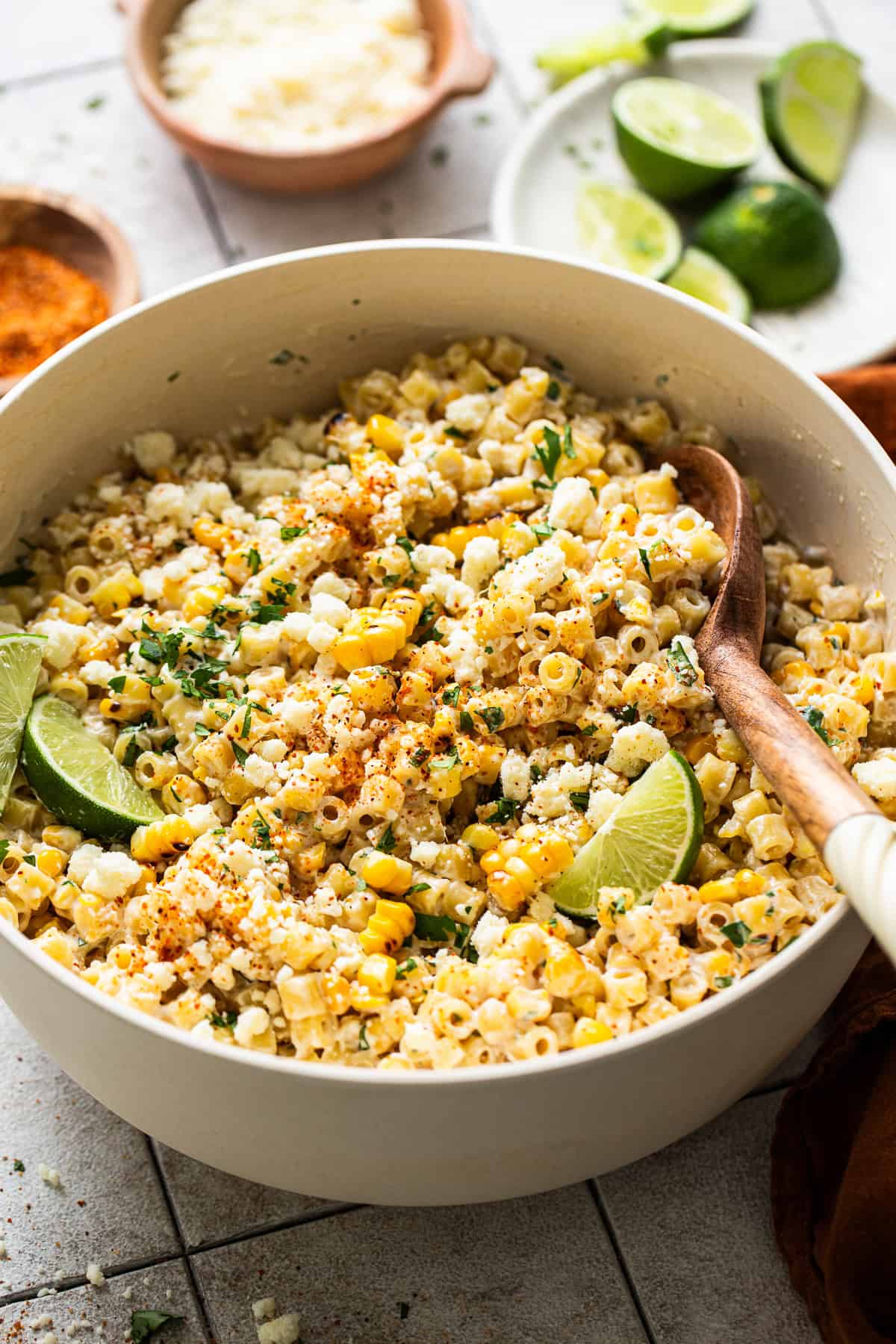 Mexican street corn pasta salad garnished with cilantro, cotija cheese, and fresh limes.