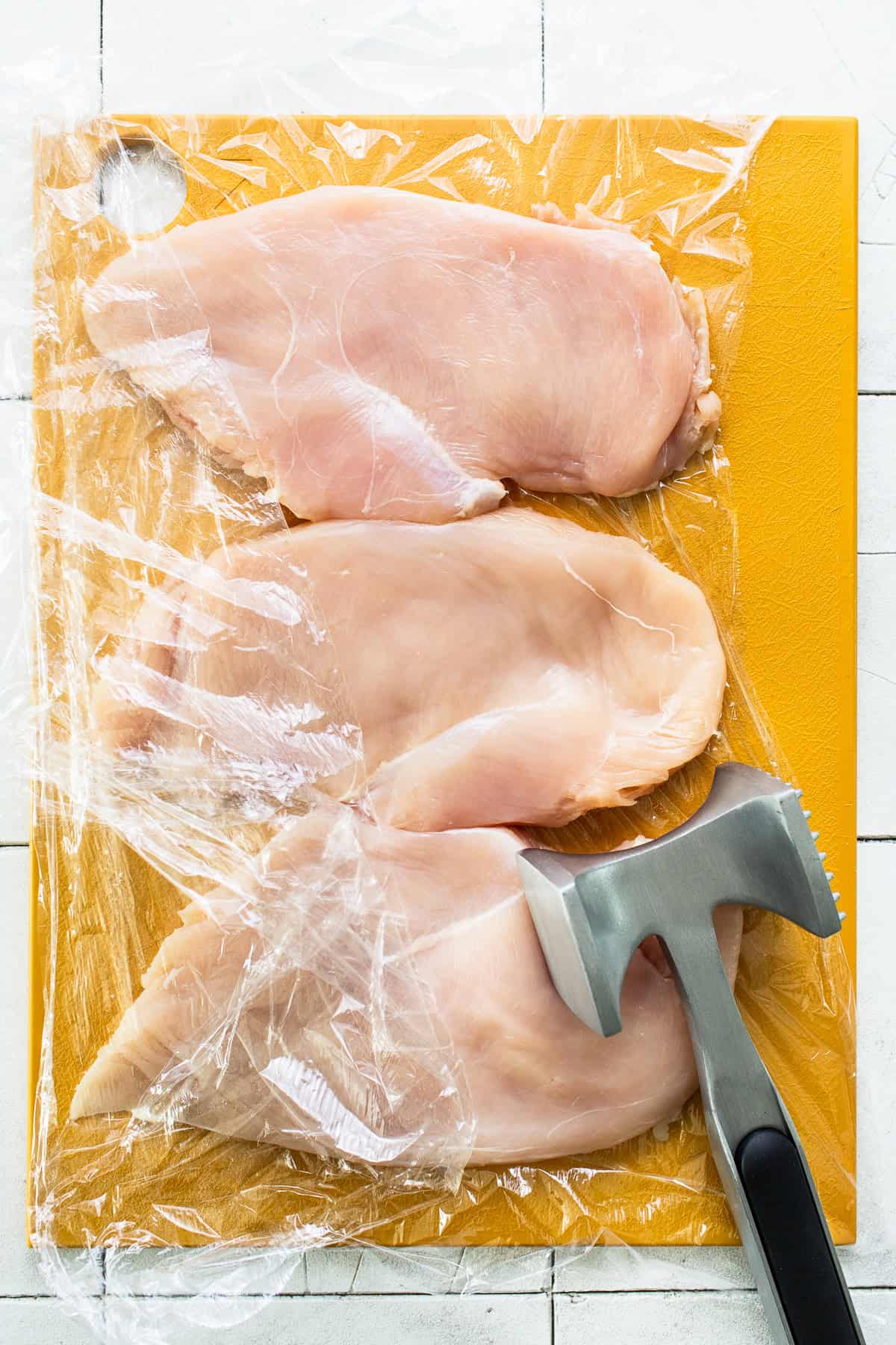 Raw chicken flattened by a meat mallet 