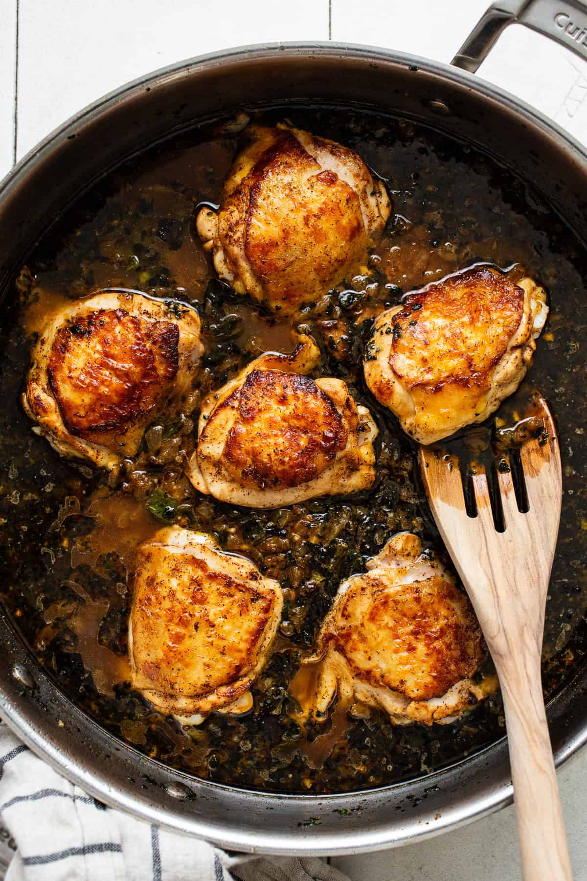 Chicken thighs in a pan simmering 