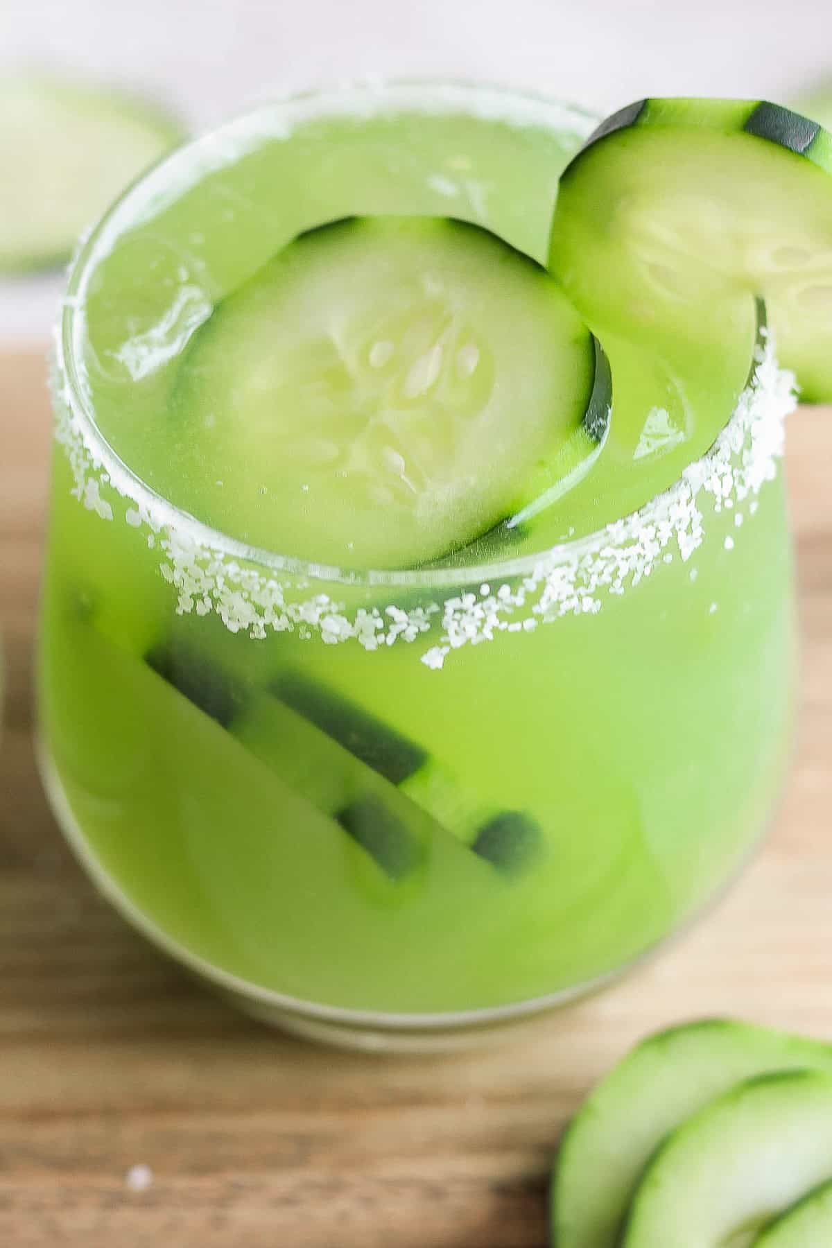 A glass of cucumber margarita in a rimmed glass.
