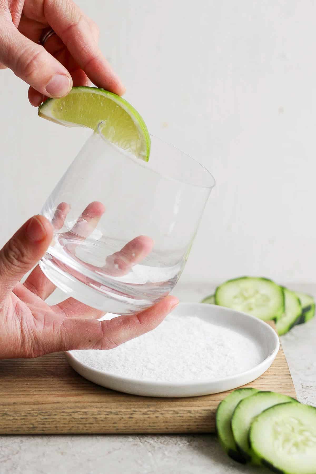 A lime wedge being run along the rim of a glass.