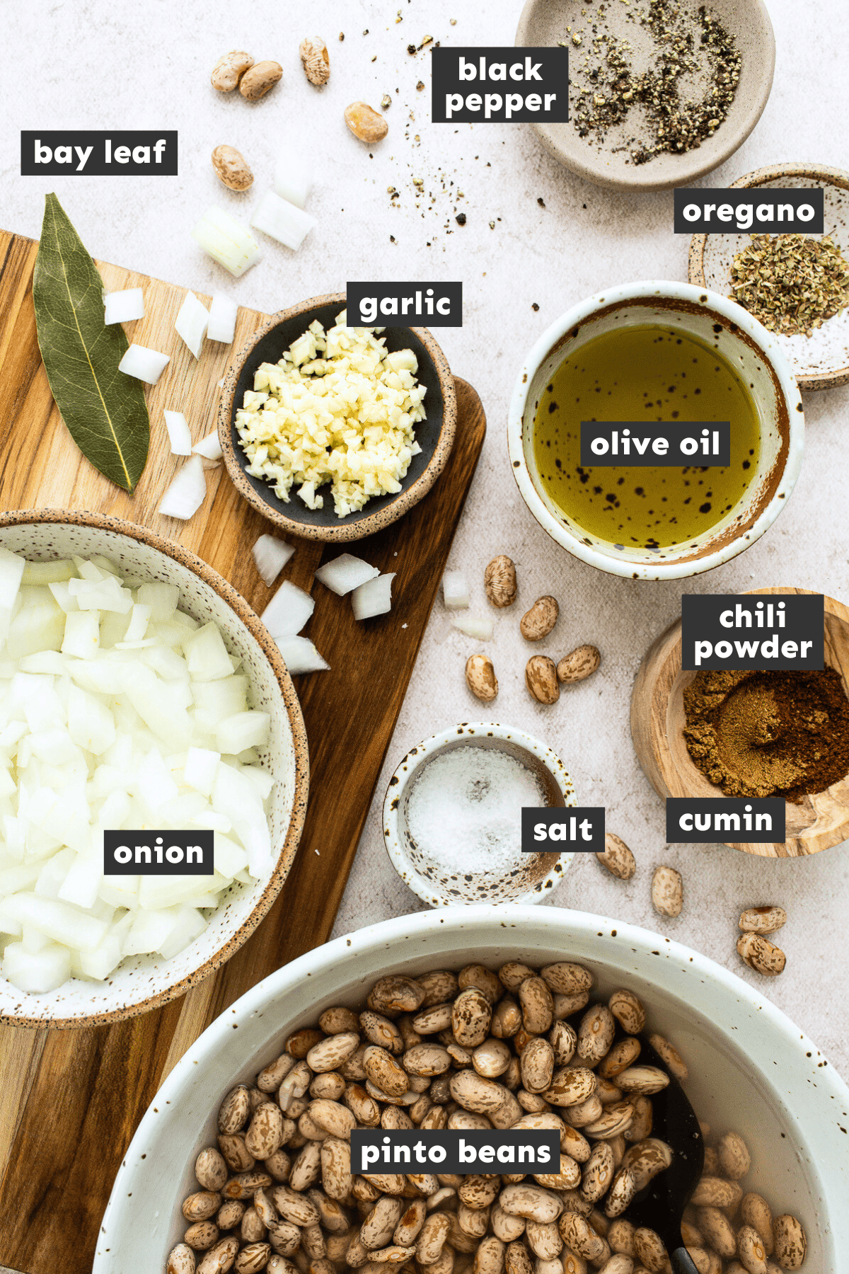 Ingredients for making pinto beans laid out in separate mixing bowls on a table.