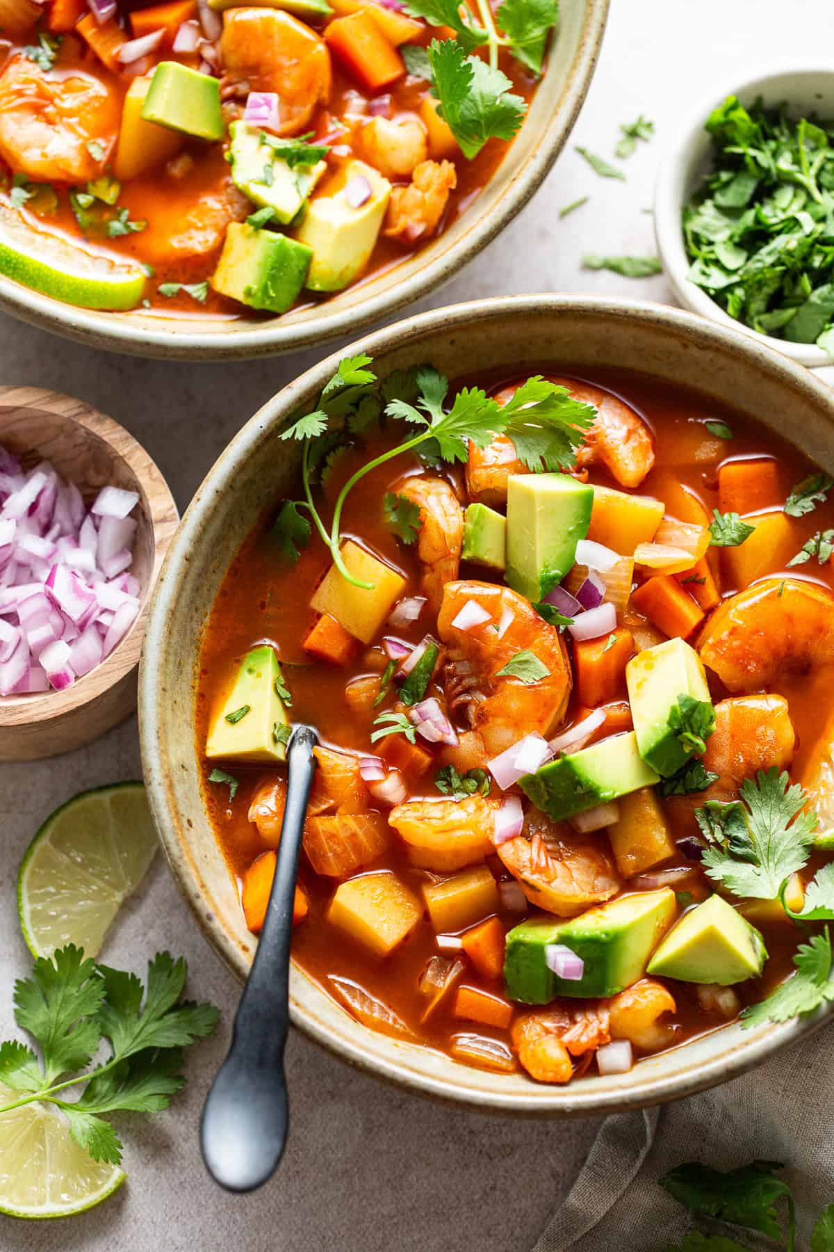 Caldo de camaron served in bowls with toppings