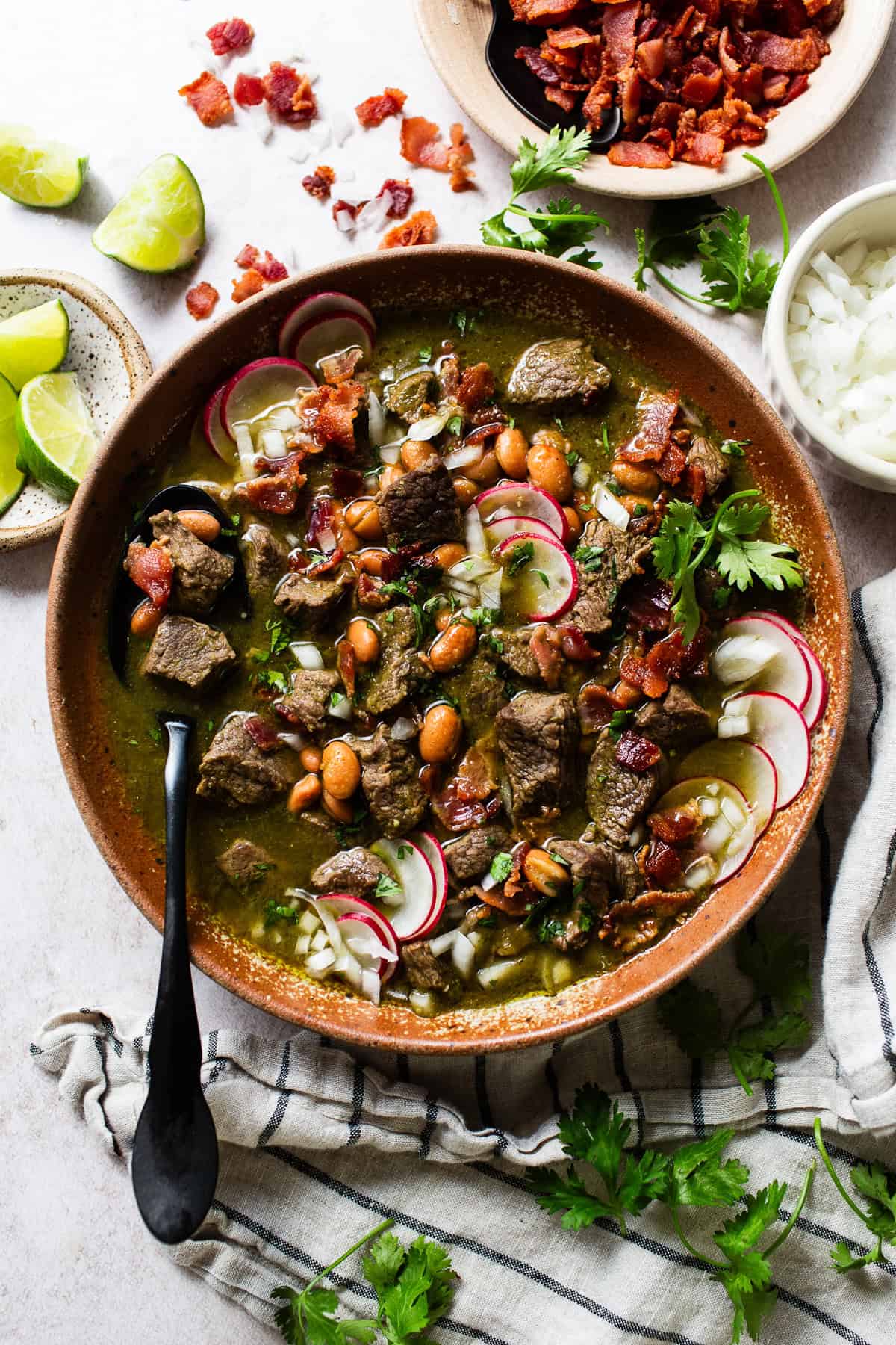 Carne en su jugo topped with bacon, onions, radish, and other toppings.