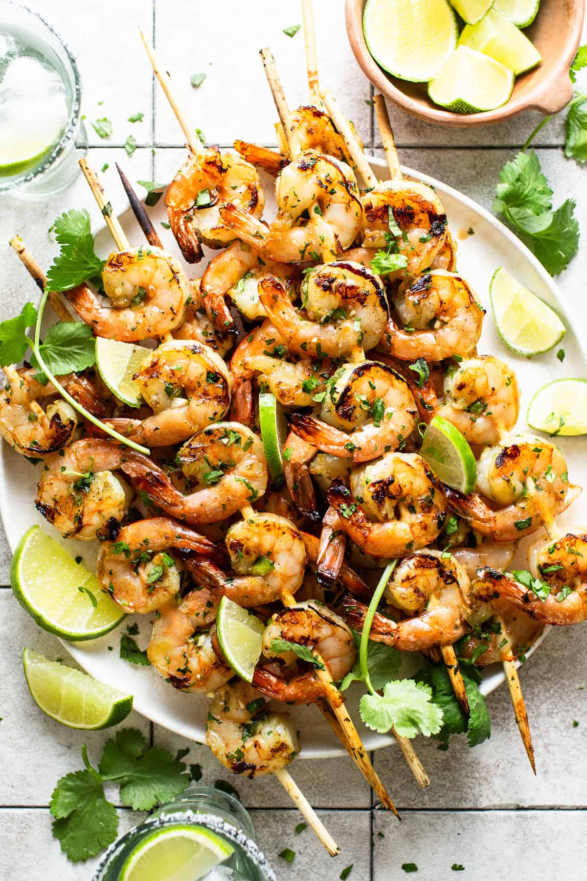 Grilled shrimp skewers plated with limes and cilantro.