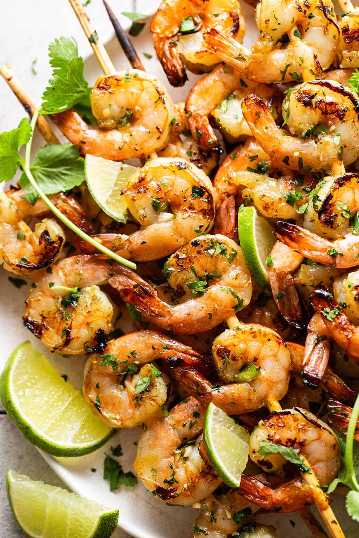 Grilled shrimp skewers plated with limes and cilantro.