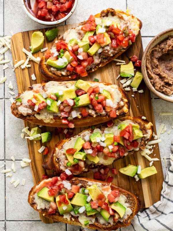 Traditional Mexican molletes topped with refried beans, cheese, pico de gallo, and avocado.