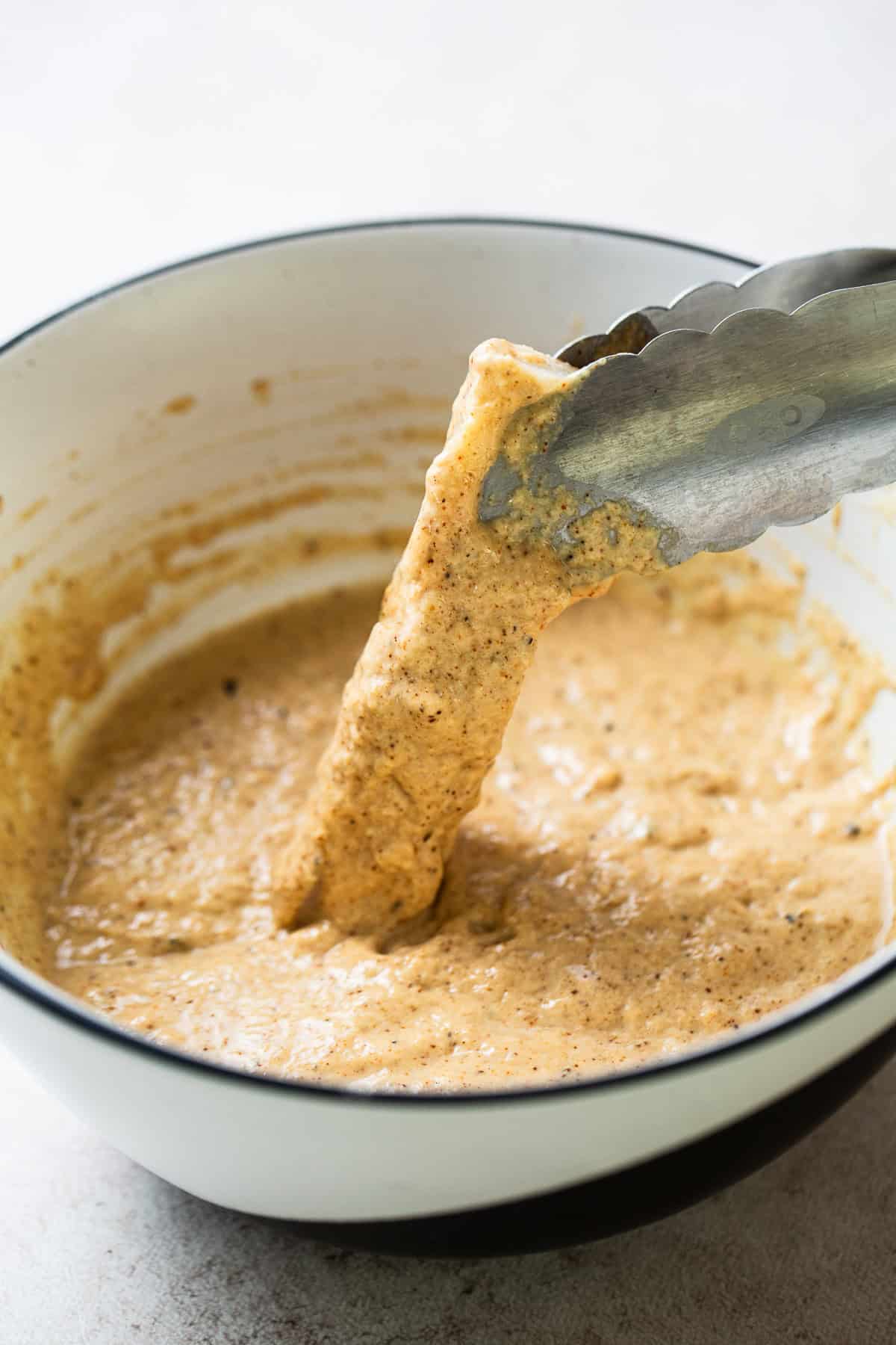 Fish being dipped in a beer batter.