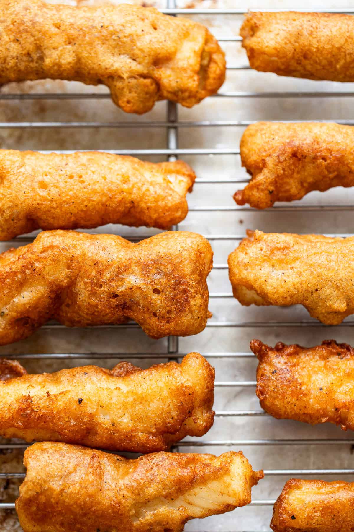 Crispy fried fish draining on a baking sheet.