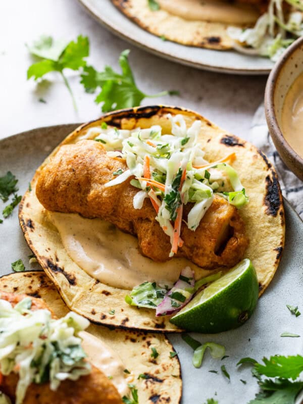 Baja fish tacos served with chipotle lime crema and topped with a creamy cabbage slaw on a plate