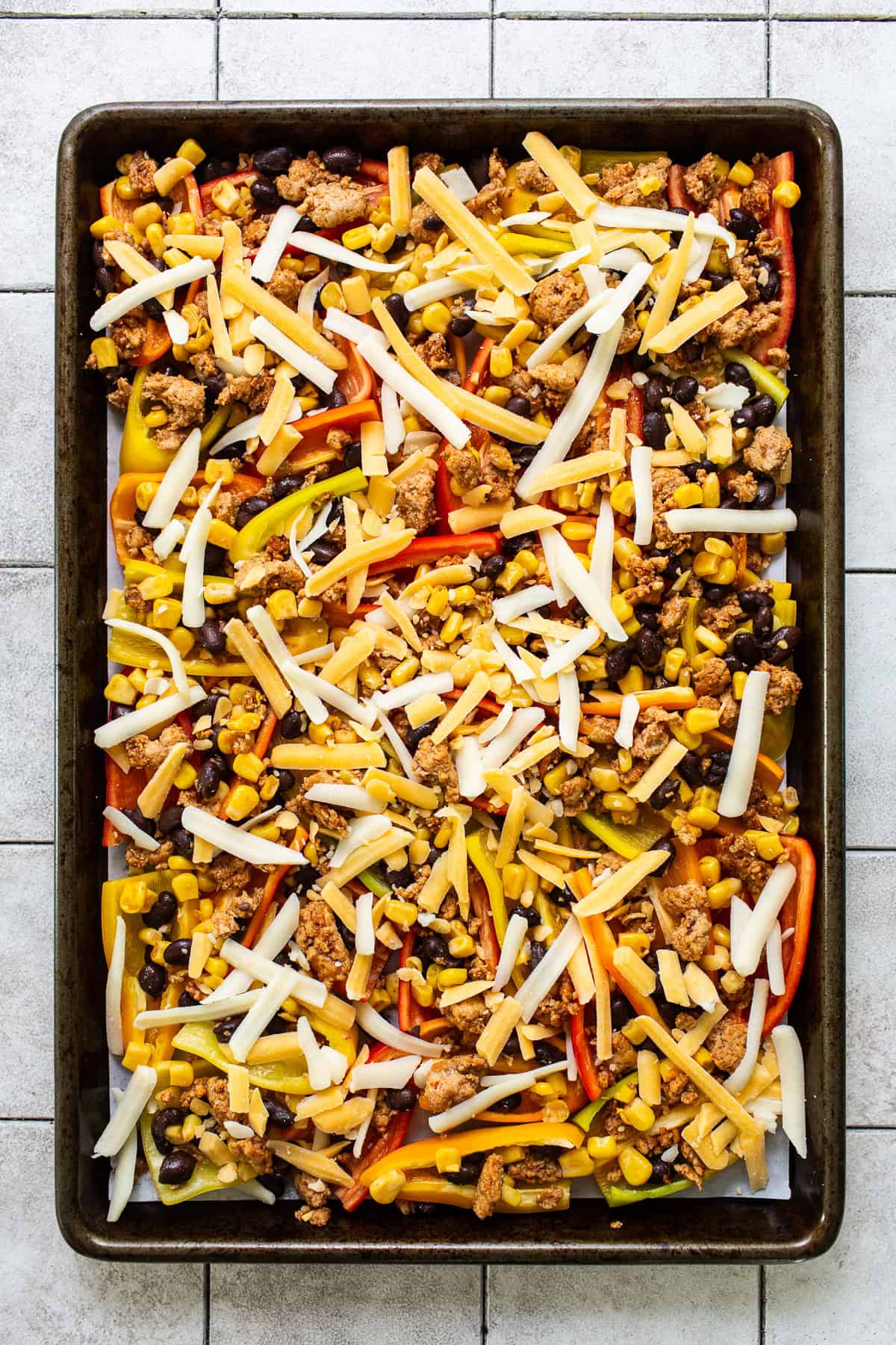 Sliced bell peppers on a sheet pan topped with a ground beef or turkey mixture and lots of shredded cheese.